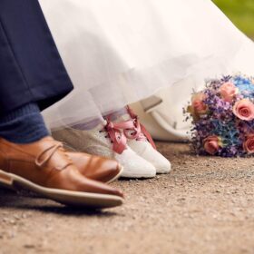 Brautpaar zeigt Schuhe und Hochzeitsstrauss - Schlosspark Celle © Hochzeitsfotograf www.hochzeitsverliebt.de 